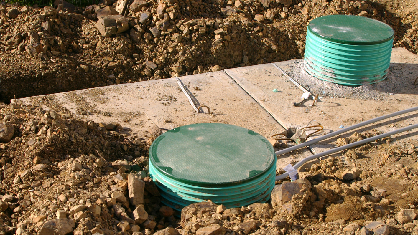 A pile of dirt next to a green water tank